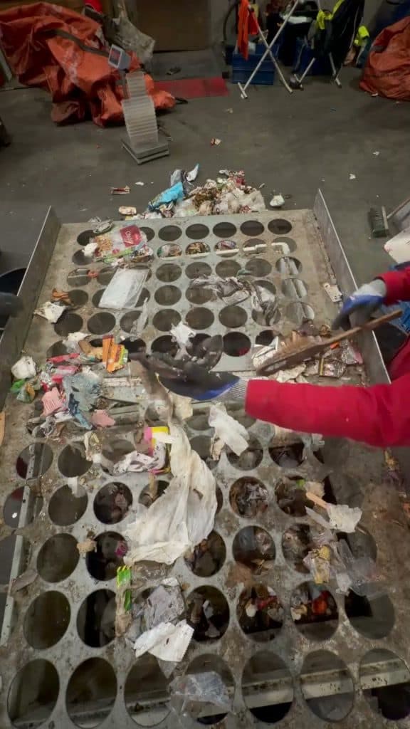 Opérateur triant les déchets sur la table de criblage percée lors d'une campagne de caractérisation
