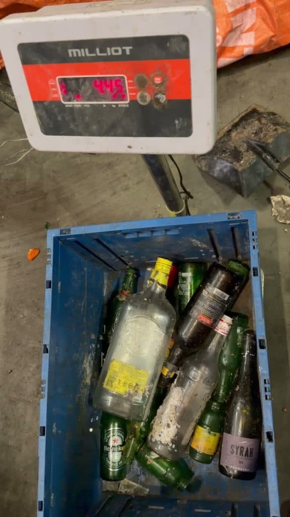 Bac de verre pesé sur une balance lors d'une campagne — l'afficheur indique 4,45 kg